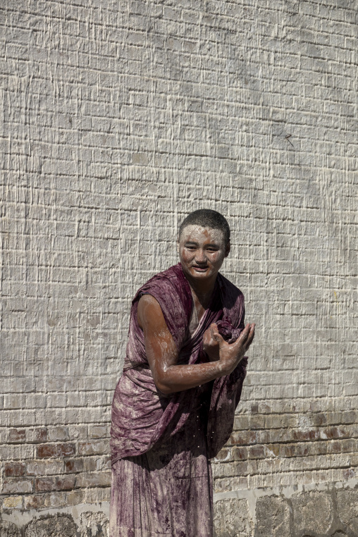 Tibetan monk enjoying a water fight after the yearly renovation of Rongwo monastery, Tongren County, Longwu, China