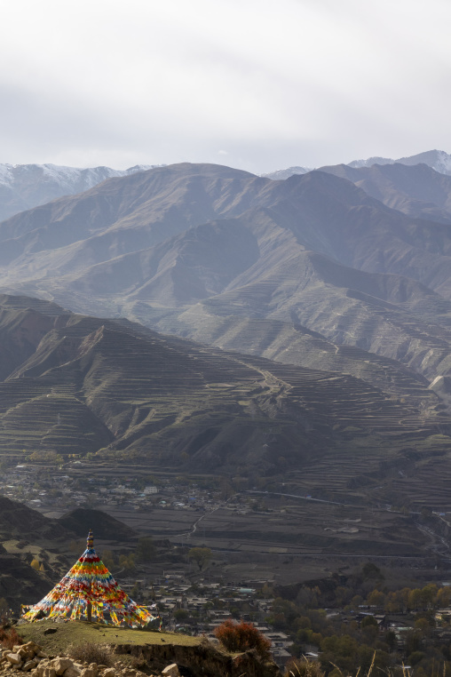 Prayer flag draped stupa overlooking a terraced valley, Tongren County, Longwu, China