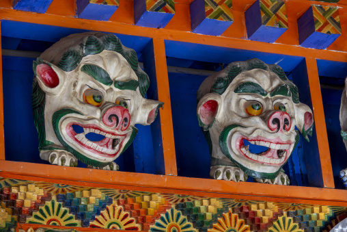 Carved guardian masks decorate a wooden beam at Bongya monastery, Qinghai Province, Mosele, China