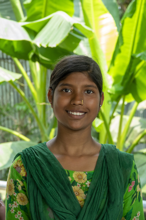 Portrait of a smiling teenage girl among banana leaves, Khulna D