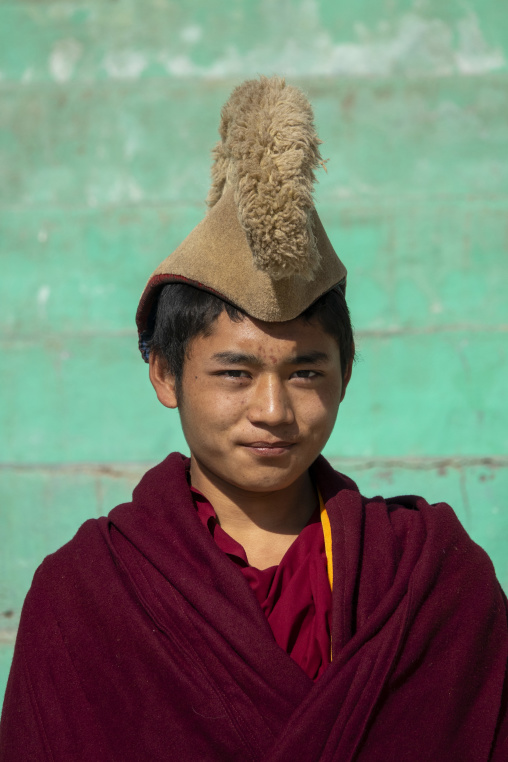 Close-up portrait of a young Tibetan monk of the Gelug or Yellow Hat sect wearing a traditional hat at Bongya monastery, Qinghai Province, Mosele, China