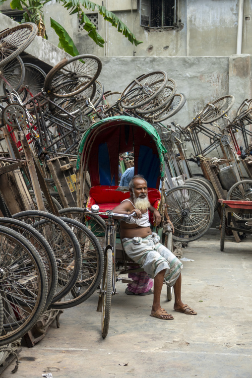 Elderly bearded rickshaw puller resting in his cycle rickshaw am