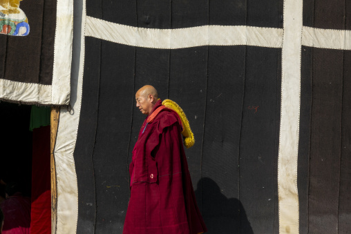 A Buddhist monk walks past a decorated prayer tent at Labrang monastery, Gansu Province, Labrang, China