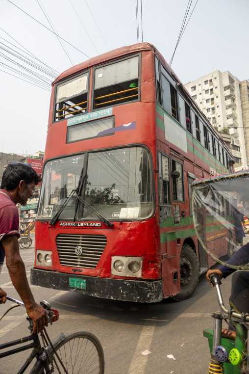 Vintage red double-decker bus navigating traffic past cyclists i