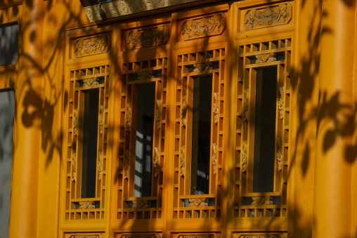 Carved wooden lattice windows glow golden at Dong Gong Guan mansion, Gansu Province, Linxia, China