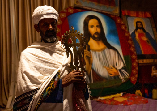 Portrait of an ethiopian orthodox priest holding a cross inside a rock-hewn church, Amhara Region, Lalibela, Ethiopia