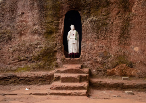 Ethiopian woman pilgrim praying in a rock-hewn church, Amhara Region, Lalibela, Ethiopia