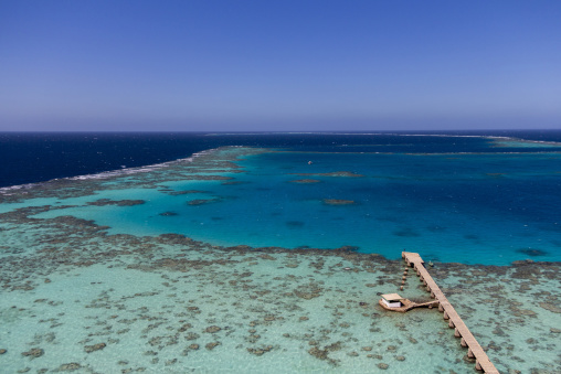 Aerial view of the turquoise lagoon enclosed by Sanganeb reef with a small pier and building, Red Sea State, Sanganeb, Sudan