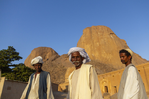 Three men in traditional dress stand near the Tomb of Hassan al Mirghani at the base of the Taka mountains, Kassala State, Kassala, Sudan
