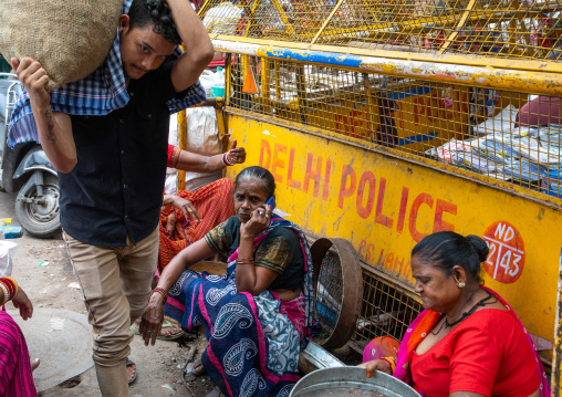 Man carrying bags in the middle of sitting women in old Delhi, Delhi, New Delhi, India