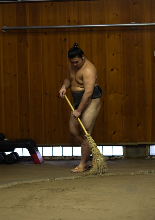 Sumo wrestler brooming the dohyo in Tatsunami Beya sumo stable, Kanto region, Tokyo, Japan