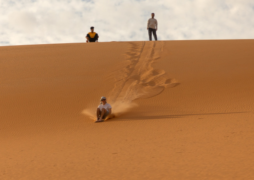 Tourist making sandboarding in the Rub al Khali dunes desert, Najran Province, Thar, Saudi Arabia