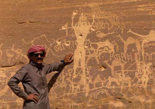 Saudi man in front of petroglyphs depicting Aliya the goddess of fertility, Najran Province, Thar, Saudi Arabia