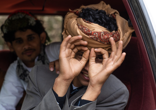 Young man in a car mimics the photographer, Asir province, Sarat Abidah, Saudi Arabia