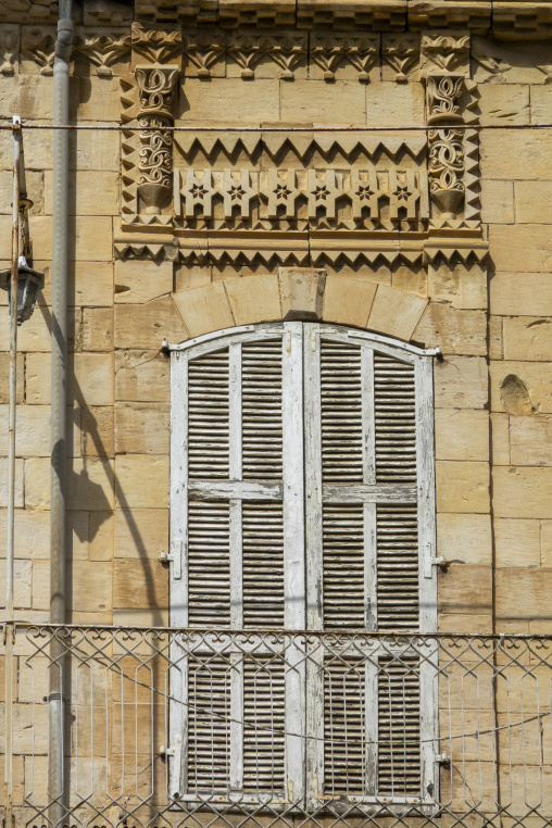 A weathered wooden shutter sits beneath an intricately carved stone frieze with star patterns, Beqaa Governorate, Zahle, Lebanon