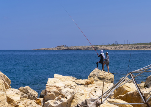 Lebanese couple fishing on rocks, North Governorate, Anfeh, Lebanon