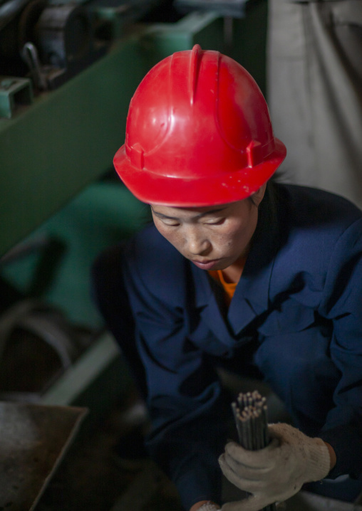 North Korean worker woman wearing a red helmet in a factory, South Pyongan, Nampo, North Korea