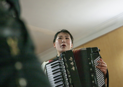 North Korean waitress in a restaurant playing accordion, DGC, Pyongyang, North Korea