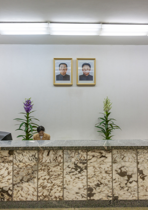 Employee in Grand people's study house below the portraits of the Leaders, DGC, Pyongyang, North Korea