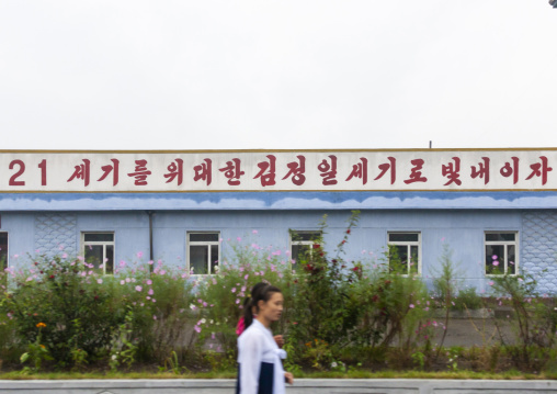 Women passing in front of a propaganda billboard about 21 century, South Hamgyong, Hamhung, North Korea