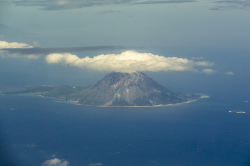 Aerial view of a volcanic peak covered by a cloud from an airpla