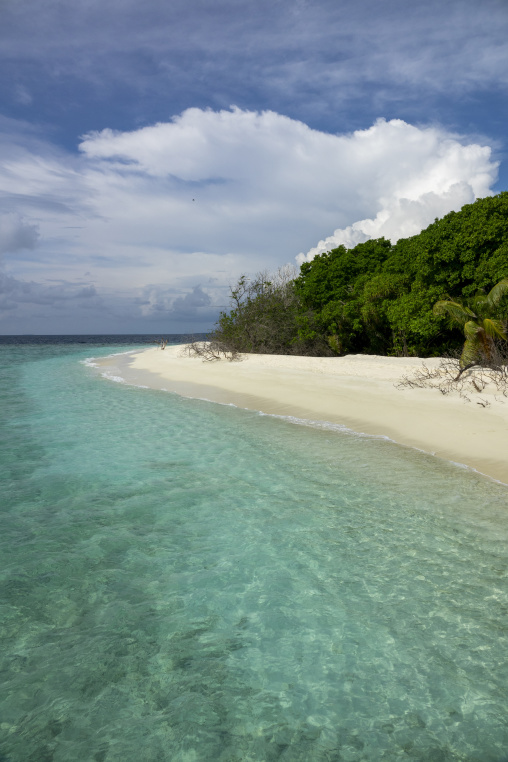 Turquoise water washes over a sandy point beneath a cloudy sky, Baa Atoll, Soneva Fushi, Maldives