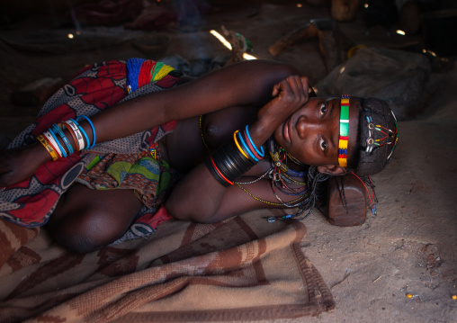 Muhacaona tribe woman resting on her wooden headrest inside her hut, Cunene Province, Oncocua, Angola