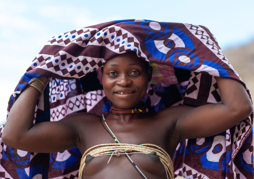 Mucubal tribe woman putting a colorful headwear, Namibe Province, Virei, Angola