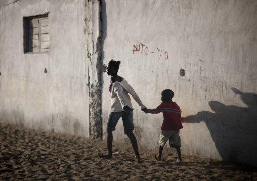 Woman Holding A Boy S Hand Along A Wall In Tombwa, Angola