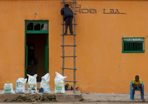 Man Painting The Facade Of His Store On A Ladder, Angola