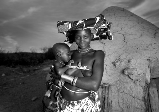 Mucubal Woman Holding Her Baby In Front Of Her Hut, Virie Area, Angola