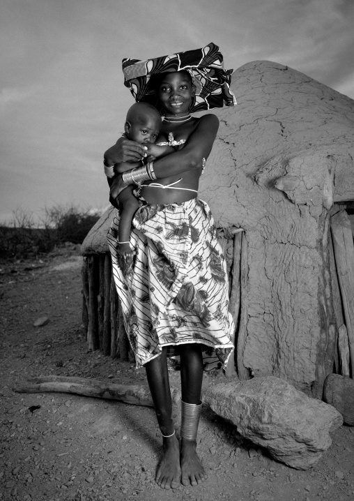 Mucubal Woman Holding Her Baby In Front Of Her Hut, Virie Area, Angola