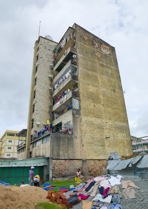 Woman Doing Their Laundry At The Bottom Of Their Building Riddled With Bullet Impacts From Civil War, Huambo, Angola