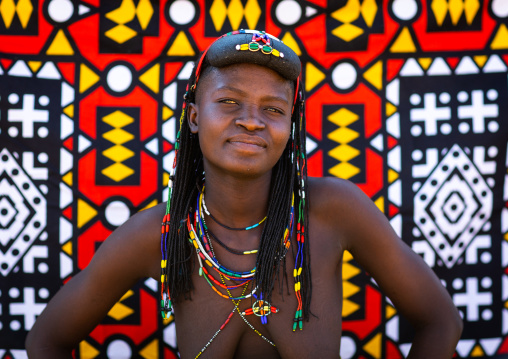 Portrait of a muhakaona tribe woman in front of a colorful printed cloth, Cunene Province, Oncocua, Angola
