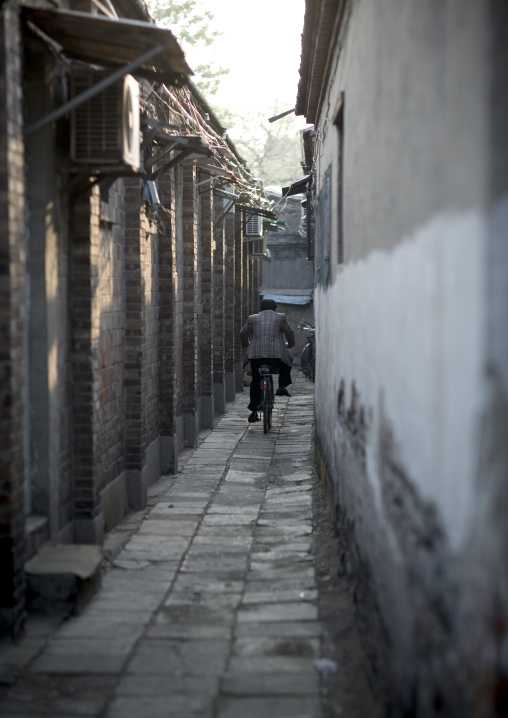 Man Riding A Bicycle In A Narrow Hutong Allay, Beijing China