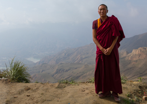 Portrait of a tibetan monk in Shachong monastery with the yellow river in the back, Qinghai Province, Wayaotai, China