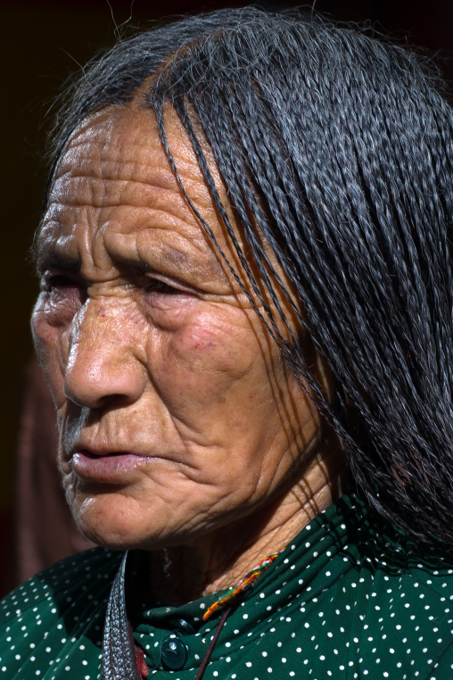 Tibetan pilgrim woman with braided hair in Rongwo monastery, Tongren County, Longwu, China
