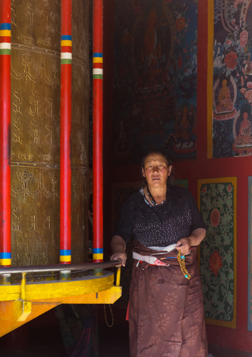 Tibetan woman turning prayer wheels in a Rongwo monastery, Tongren County, Longwu, China