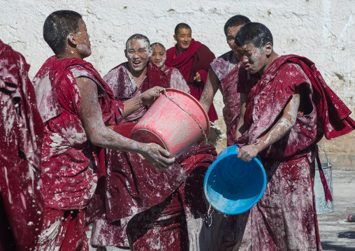 Tibetan monks enjoying a water fight after the yearly renovation of the Rongwo monastery, Tongren County, Longwu, China