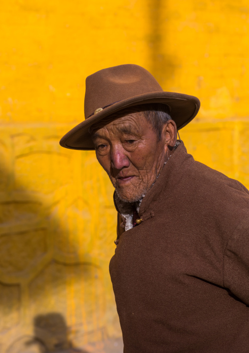 Old tibetan pilgrim man with a hat in Rongwo monastery, Tongren County, Longwu, China