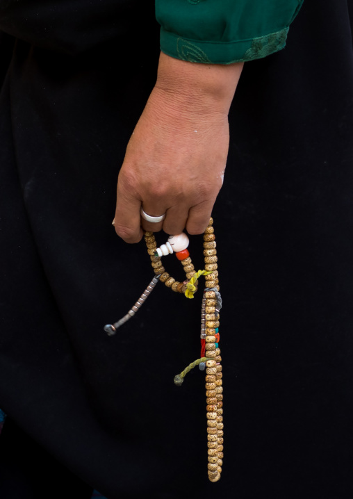 A tibetan pilgrim fingers her prayer beads in Rongwo monastery, Tongren County, Longwu, China
