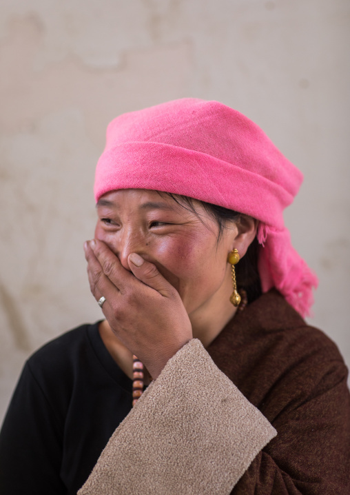 Portrait of a tibetan nomad woman with a pink headwear laughing, Qinghai province, Tsekhog, China