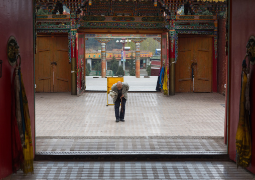 Old tibetan man bowing in front of the entrance in Hezuo  monastery, Gansu province, Hezuo, China