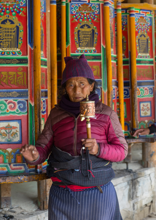 Tibetan pilgrim woman with a prayer wheels in her hand in Labrang monastery, Gansu province, Labrang, China