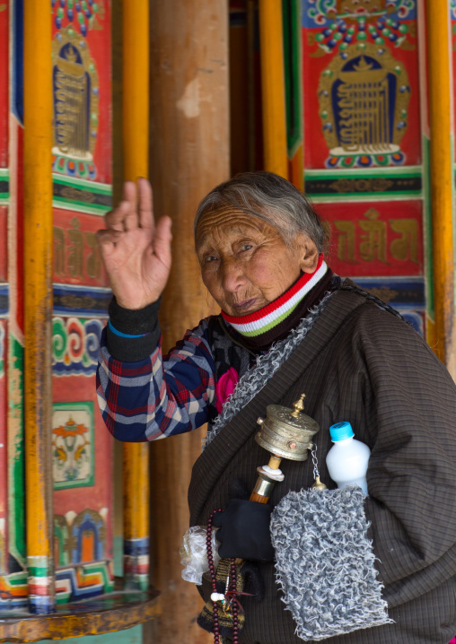Tibetan pilgrim woman turning huge prayer wheels in Labrang monastery, Gansu province, Labrang, China