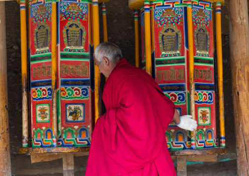 Tibetan monk turning huge prayer wheels in Labrang monastery, Gansu province, Labrang, China