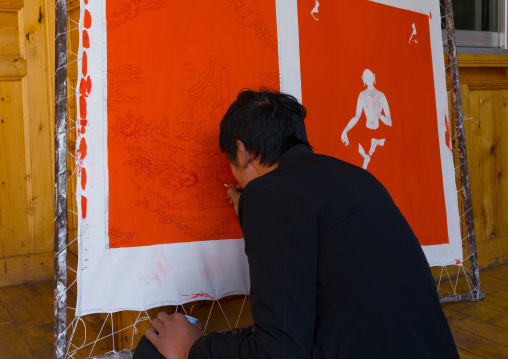 Tibetan artist painting a thangka at a workshop, Qinghai province, Wutun, China