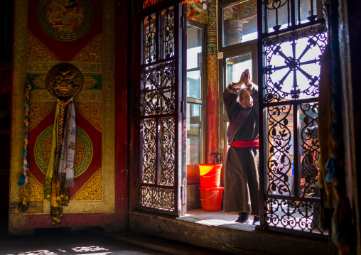 Tibetan woman praying at the entrance of a temple in Rongwo monastery, Tongren County, Longwu, China