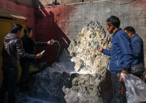 Tibetan men throwing milk in a temple of Rongwo monastery, Tongren County, Longwu, China