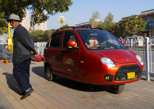 Cute small three-wheeled red chinese taxi in the street, Gansu province, Linxia, China